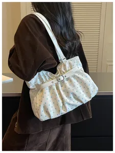Primer plano detallado del bolso de hombro blanco con lunares azul claro y fruncidos.