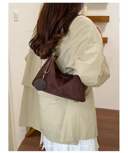 Stylish brown suede shoulder bag for women, retro underarm bag with chic woven charm pendant.