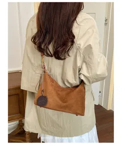 Brown suede shoulder bag detail view showcasing soft texture, retro style and metal hardware.