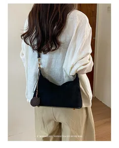 Detailed shot of a black suede underarm shoulder bag showcasing its minimalist retro style and charm.