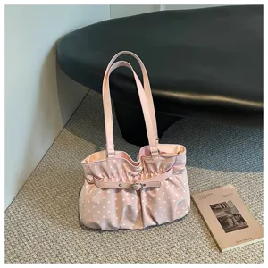 Vista detallada de un elegante bolso de hombro plisado con lunares rosas y diseño suave.