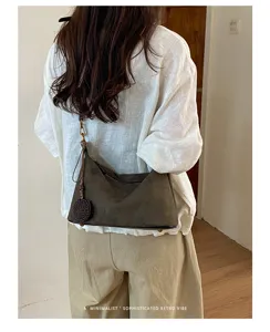 Suede shoulder bag for women, retro underarm casual purse with woven pendant detail.