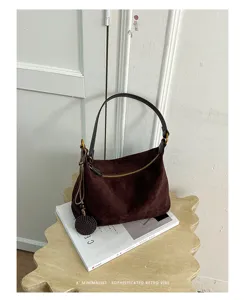 Dark brown suede shoulder bag detail, soft texture, chic zipper and elegant charm.