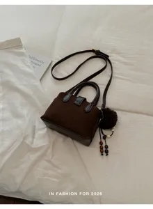 Sac à bandoulière marron stylé pour femme, design carré tendance avec charmant pompon.
