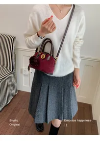 Sac bandoulière rétro en suédine bordeaux style coréen avec poignée et pompon duveteux.