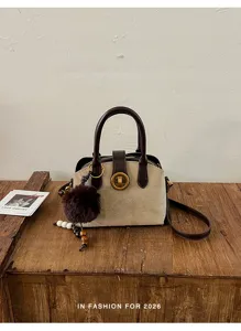 Élégant sac à main en suède vintage avec charmant pompon et fermeture rotative chic.