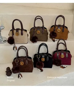 Vue détaillée du sac à main tendance en suède avec pompon duveteux et élégant fermoir tournant.