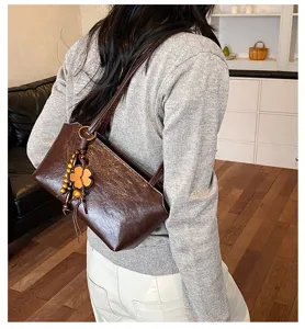 Vista detallada del elegante bolso de hombro marrón retro con colgante de trébol.