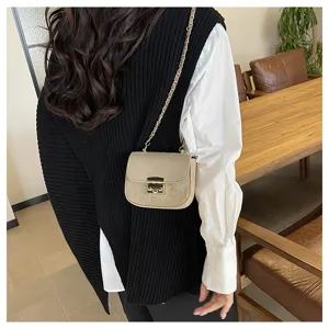 Nahaufnahme einer eleganten Wildleder-Umhängetasche mit Kette und schickem Metallverschluss.