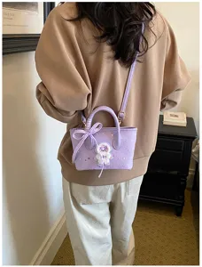 Purple mini handbag detail showcasing cute plush bear decor and plaid bow on handle.