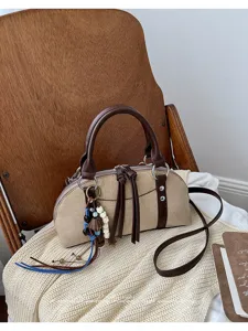Detail van de stijlvolle retro handtas met bruin lederen handvat en schattige hanger.