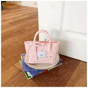 Cute pink canvas handbag detail showing star print, bear patch and plaid ribbon handle wrap.