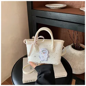 Detailed view of white mini shoulder crossbody bag with cute plush bear patch and bow ribbon.