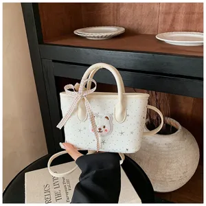 Detailed shot of a cute white mini handbag featuring a fluffy bear patch, star pattern and bow.
