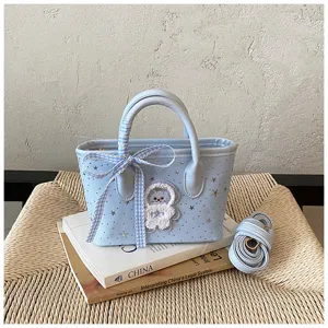 Detailed shot of a light blue tote bag with star prints, ribbon and astronaut patch.