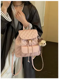 Detailed view of the pink quilted leather backpack featuring a cute bear pendant and drawstring.