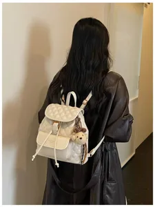 Detailed view of the stylish white quilted backpack with a cute bear charm, perfect for daily.