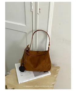Brown suede shoulder bag detail view, casual underarm style with hanging charm accessory.