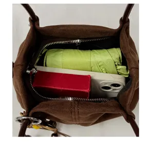 Brown suede handbag interior detail showing large capacity with daily essentials inside neatly.