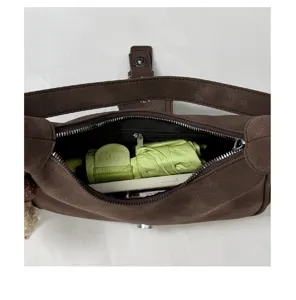 Detalle de bolso de hombro de ante marrón que muestra la amplia capacidad interior.