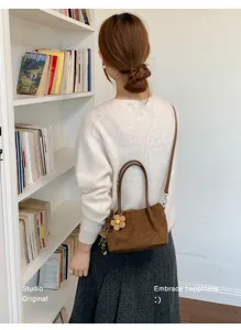 Detail view of a stylish brown suede crossbody bag with floral charm, perfect for casual daily wear.