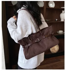 Detailed view of the brown suede shoulder bag, featuring stylish belt decor and retro design.