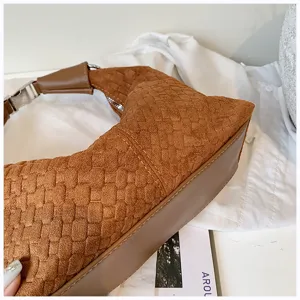 Vista detallada del bolso de hombro trenzado marrón con textura de ante y base de cuero.