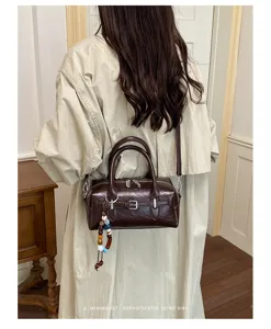 Detailed view of women retro brown leather pillow bag with stylish bead charm and straps.