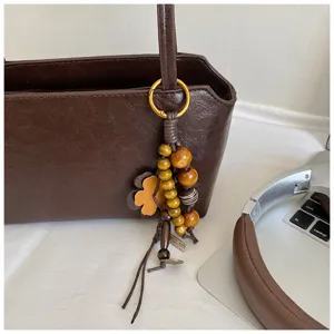 Bolso de hombro de cuero marrón con colgante de cuentas de madera estilo retro.