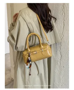 Detail shot of yellow patent leather handbag with beaded charm and retro design aesthetic.