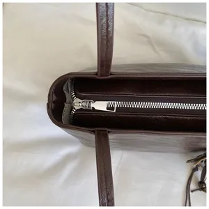 Primer plano detalle de cremallera y correa de bolso marrón retro, diseño elegante.