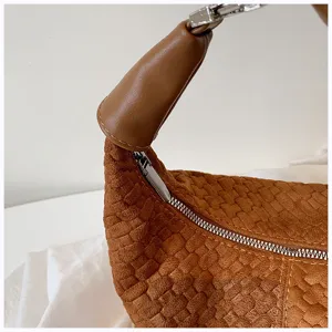 Primer plano detallado del elegante bolso de mano marrón tejido, textura y cremallera de metal.