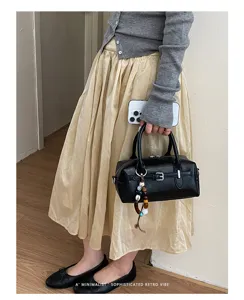 Chic black PU leather pillow handbag for women, stylish commuter crossbody bag with charm.