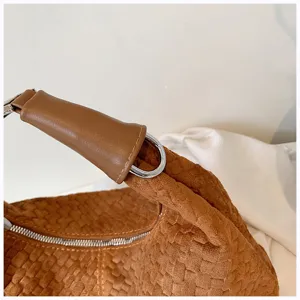 Primer plano de la correa de bolso tejida marrón y detalles metálicos, elegante accesorio de moda