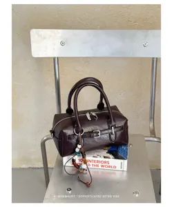 Detail shot of retro brown leather boston bag with metallic buckle and beaded charm ornament.