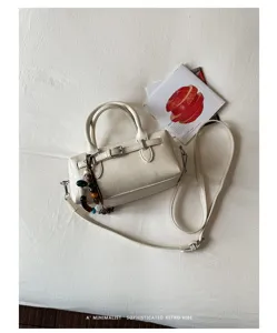 Detail shot of minimalist retro women handbag, stylish cream white PU leather pillow bag with chic bead charm.