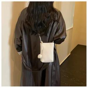 Vista di dettaglio di una mini borsa a tracolla bianca minimalista con cappotto in pelle.