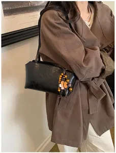 Bolso de hombro minimalista negro chic bajo el brazo con colgante de trébol de madera.