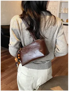 Vista detallada de un bolso de hombro retro marrón con colgante de flor de cuentas de madera.