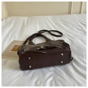Detailansicht der braunen Lederhandtasche mit Metallschrauben und eleganter Textur.