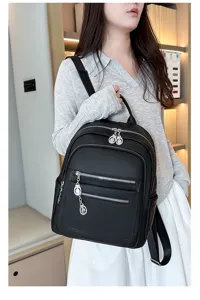 Black leather backpack detail featuring multiple zipper pockets and a stylish metal charm.