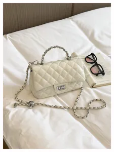 Vista dettagliata della borsa a tracolla trapuntata bianca con catena e chiusura su letto.
