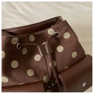 Close-up detail of brown polka dot backpack suede texture drawstring casual design.