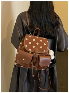 Close up detail of the brown polka dot fashion backpack showcasing front pockets and charm.