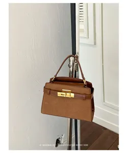 Brown suede texture handbag detail shot, featuring metallic turn-lock closure and elegant strap.