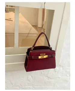 Burgundy leather handbag detail shot with gold hardware and classic retro trapezoid design