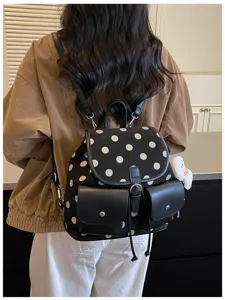 Detail shot of the stylish black and white polka dot backpack, showing front pockets and strap.