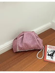 Gros plan détaillé d'une pochette rose métallique froissée ornée de perles blanches délicates.