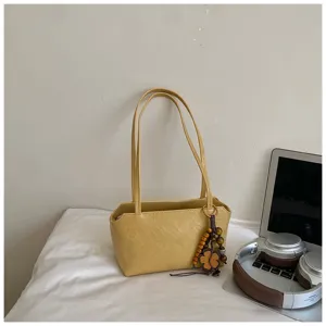 Bolso de hombro amarillo sólido minimalista con colgante floral para desplazamientos diarios.
