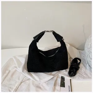 Vista detallada del elegante bolso de mano negro trenzado con asa metálica única.